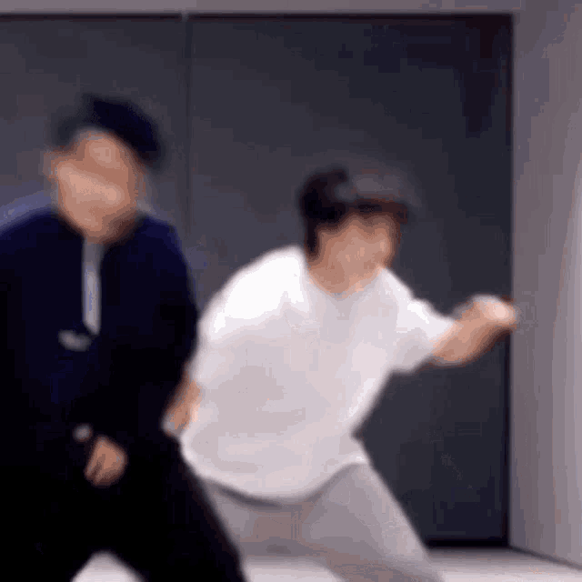 two men are dancing together in a room in front of a wall .