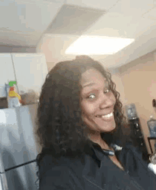 a woman with curly hair is smiling for the camera in a kitchen
