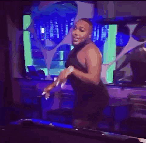 a man without a shirt is standing in a room with blue lights and a red exit sign