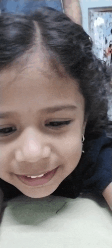 a little girl is smiling while laying on her back on a bed .