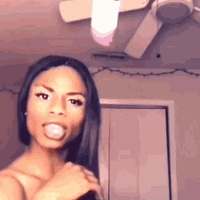 a woman is standing in front of a ceiling fan in a room .