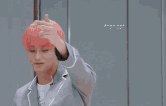 a man with pink hair is making a funny face with the words * panics * written above him