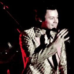 a man in a suit and tie is standing on a stage with a microphone .