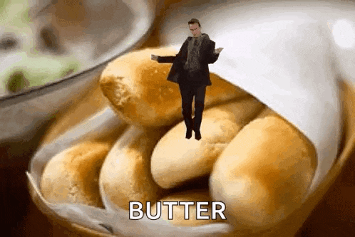 a man is dancing on top of a bowl of rolls with the word butter written on it .