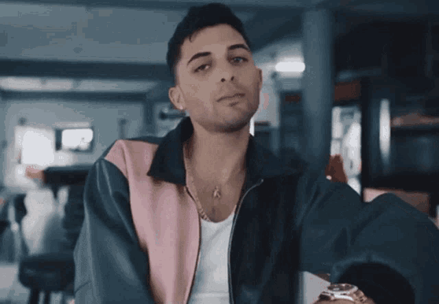 a young man wearing a pink and blue jacket and a watch