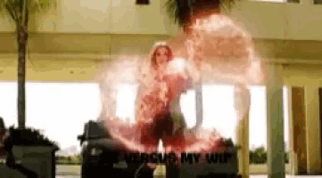 a woman is standing in front of a building with a red light coming out of her .