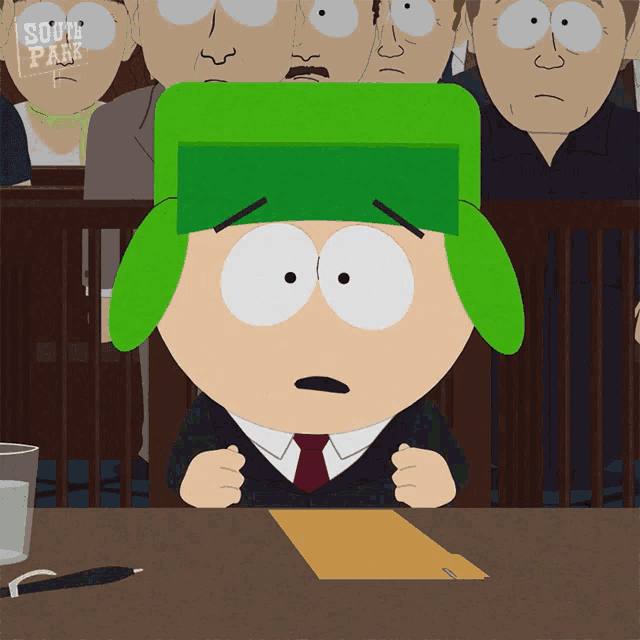 a cartoon character from south park sits at a table in front of a group of people