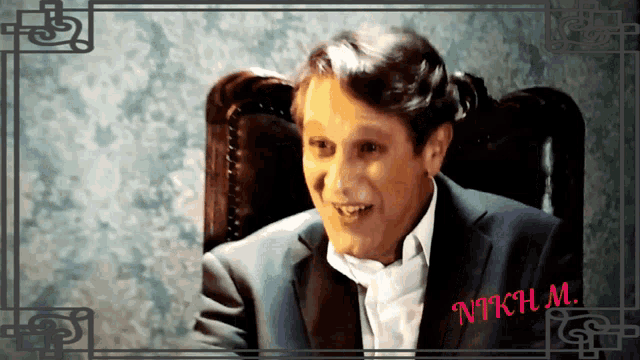 a man in a suit sits in a chair with the name nich m. on the bottom of the picture