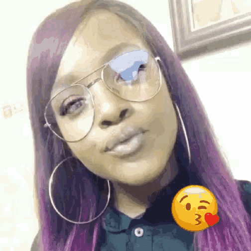 a woman with purple hair wearing glasses and hoop earrings is making a kissing face .