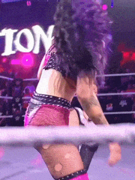 a woman in a wrestling ring with a sign that says tion in the background