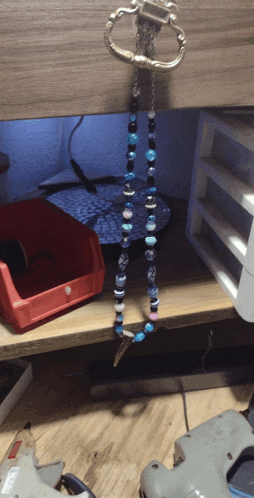 a necklace with blue and black beads is hanging from a keychain