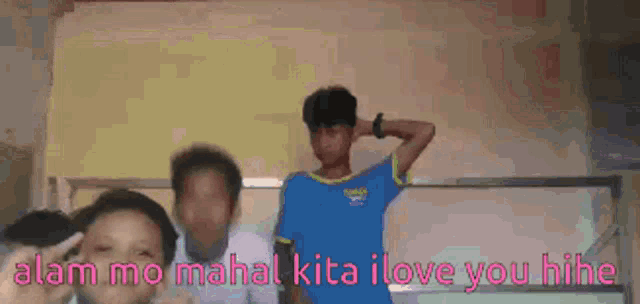a boy in a blue shirt stands in front of a white board with the words alam mo mahal kita i love you hine