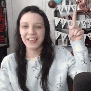 a woman wearing a blue sweater is smiling and giving a high five