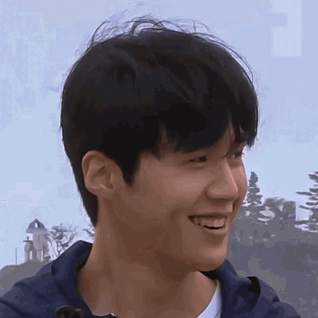 a close up of a young man 's face with trees in the background