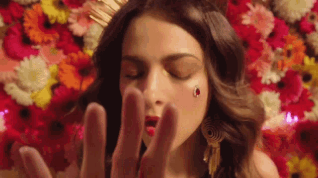 a close up of a woman 's face with her eyes closed and flowers in the background