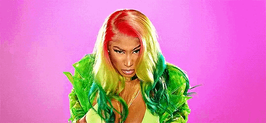 a woman with colorful hair is wearing a green jacket and a green top .