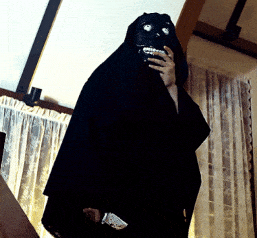 a person in a black cloak holding a knife in a room