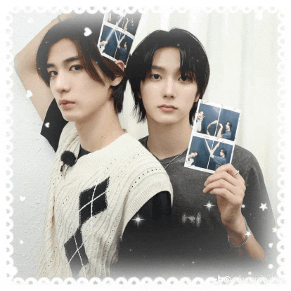 two young men are posing for a picture and one is holding a polaroid picture