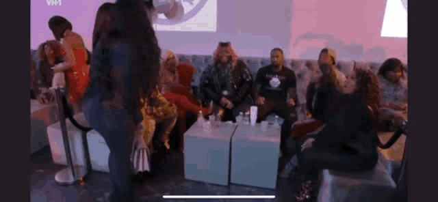a group of people are sitting in a room with a sign that says vh1 in the background