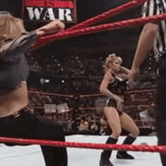 a woman is dancing in a wrestling ring with a sign that says war