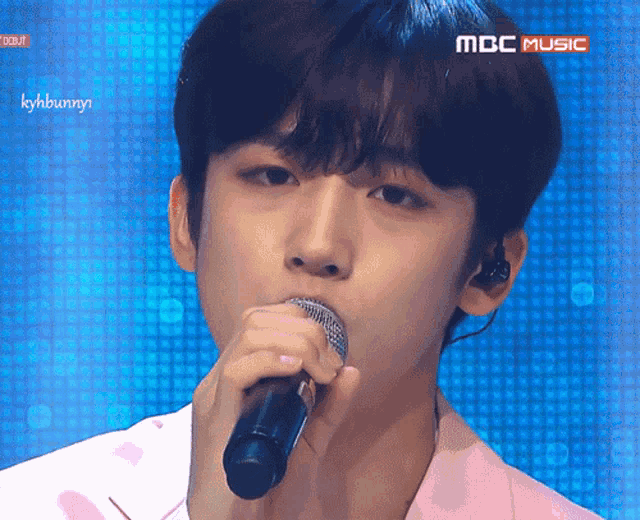 a close up of a person singing into a microphone with the words mbc music on the bottom