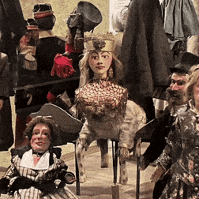 a group of puppets including a woman with a crown