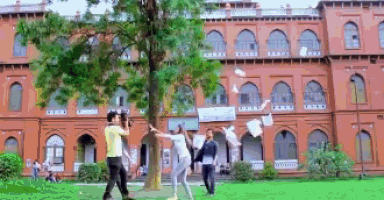 a group of people throwing papers in front of a large brick building