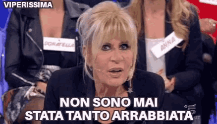 a woman with blonde hair is sitting in front of a group of women and says non sono mai stata tanto arrabbiata .