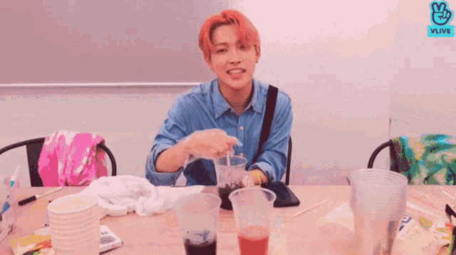 a man with red hair is sitting at a table with a vlive logo on the bottom
