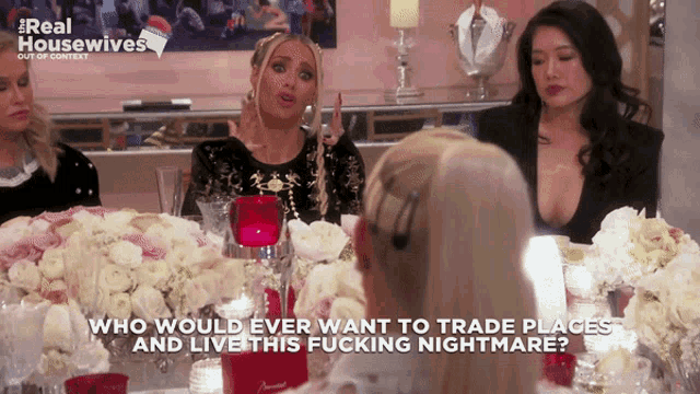 a group of women are sitting at a table with flowers and candles and one woman says who would ever want to trade places