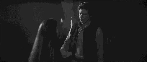 a black and white photo of a man and a woman standing next to each other in a dark room .