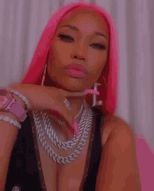 a close up of a woman with pink hair wearing a black top and a necklace .