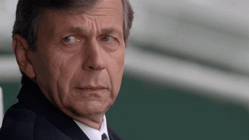 a man wearing a suit and tie is looking at the camera .