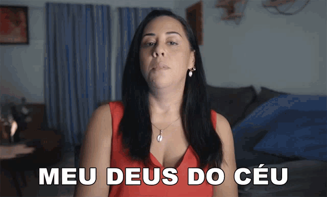 a woman in a red top says " meu deus do ceu " in front of a bed