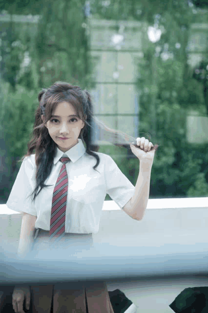 a girl in a school uniform holds her hair in her hand