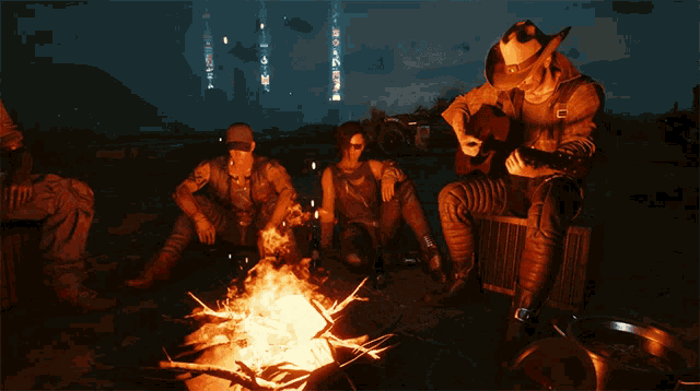 a group of people are sitting around a campfire with one man playing a guitar