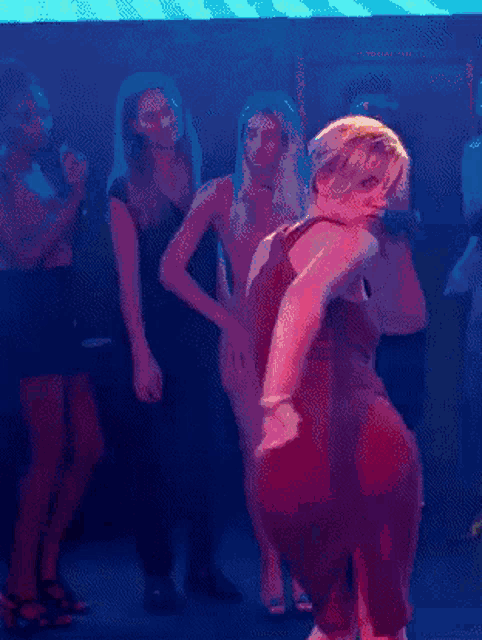 a woman in a red dress is dancing in a dark room