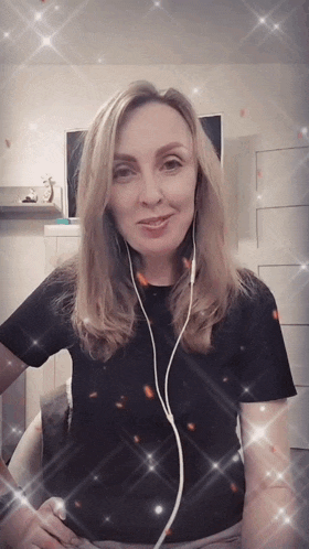 a woman wearing headphones and a black shirt stands in a room