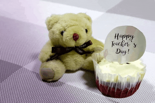 a teddy bear sitting next to a cupcake that says happy teacher 's day .