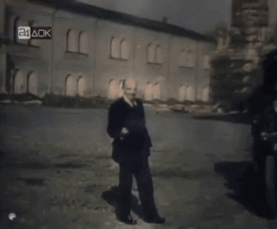 a man in a suit and tie stands in front of a building that says 24 aok on it