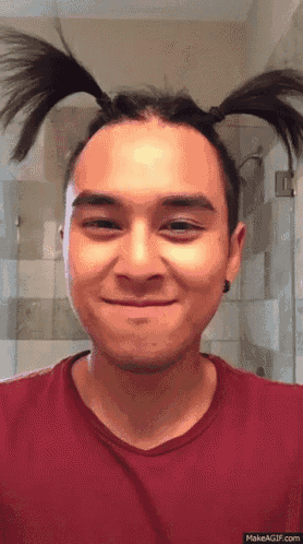 a man with two pigtails on his head looks at the camera