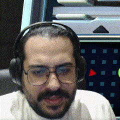 a man wearing glasses and headphones is smiling in front of a computer screen