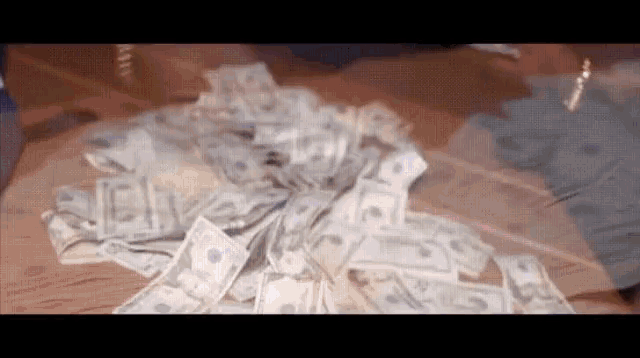 a pile of money is laying on a wooden table .