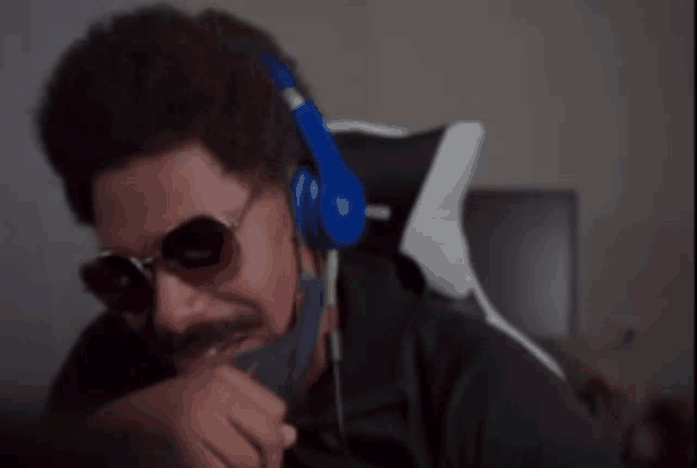 a man wearing sunglasses and headphones is sitting in an office chair