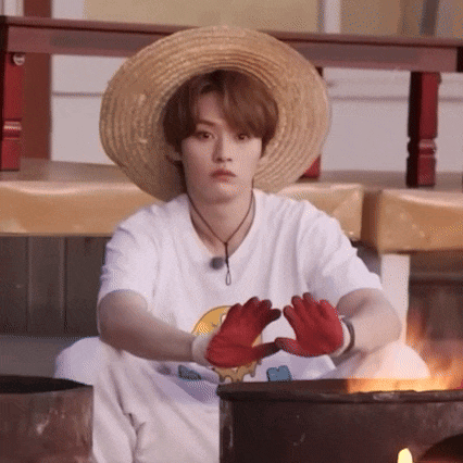 a young man wearing a straw hat and red gloves is making a heart with his hands .