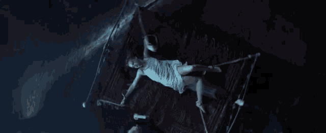 a woman in a white dress is laying on a bed with a rope around her waist .