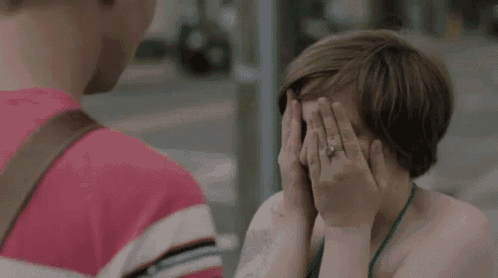 a woman is covering her face with her hands in front of a man .