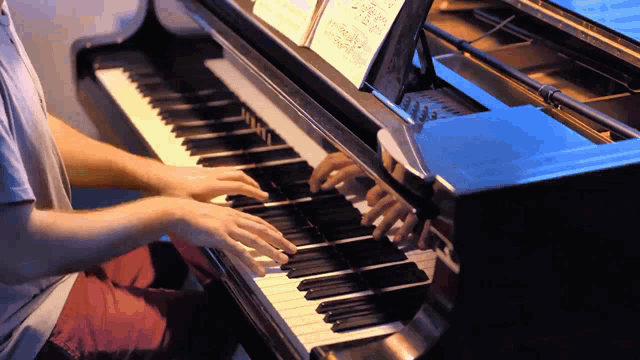 a man is playing a piano with a sheet of music on top