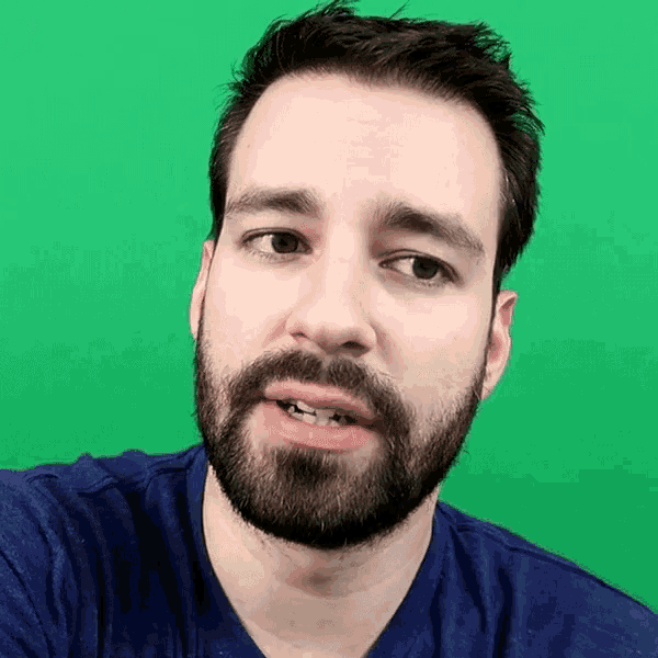 a man with a beard wearing a blue shirt is looking at the camera