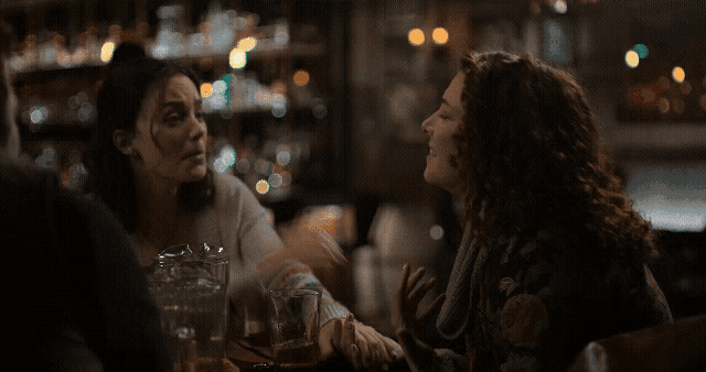 two women are sitting at a table and one of them is saying " me too "